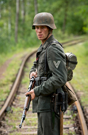 Der Überläufer, Szenenbild: ein junger Mann in Wehrmachtsuniform steht mit seiner Waffe in einem Gleisbett. (© NDR/Dreamtool Entertainment)