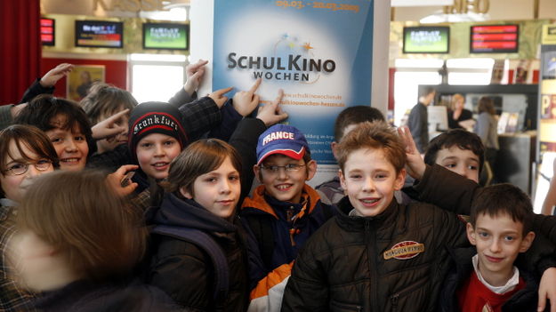 SchulKinoWochen in Hessen: Kinder stehen im Kinofoyer vor einem Plakat der Schulkinowochen (© Vision Kino)