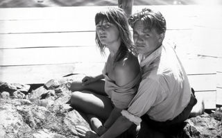 Die Zeit mit Monika, Szenenbild aus dem Schwarz-Weiß-Film: Ein junges Paar sitzt am Meer eng zusammen und blickt in die Kamera (© picture alliance/United Archives | 90061)