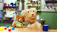 Knopf & Knöpchen, Szenenbild: Ein großer und ein kleiner Teddybär sitzen an einem Küchentisch. (© Film-Line Productions GmbH)