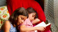 Stadtpinguin, Szenenbild: Zwei Mädchen liegen aneinandergekuschelt im Bett und lesen. (© DFFB)