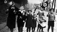 Berlin 1933 - Tagebuch einer Großstadt, Szenenbild: Das historische Schwarzweißbild zeigt eine Straßenszene mit lächelnden Kindern, die Hakenkreuzfähnchen in den Händen halten (© Scherl/Süddeutsche Zeiting Photo)
