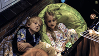Busters Welt, Szenenbild: Ein blonder Junge und ein blondes Mädchen sitzen aneinandergekuschelt auf einem Balkon und schauen nach oben. (© Kinostar Filmverleih)