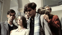 Szenenbild aus dem Drama "Die weiße Rose" (1982): Eine junge Frau und ein junger Mann gehen eine Treppe herunter. Hinter ihnen sind vier Männer zu sehen. (© picture alliance/United Archives/kpa)
