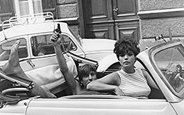 Zur Sache, Schätzchen (Szenenbild, Martin (Werner Enke) und Barbara (Uschi Glas) in einem VW-Käfer-Cabrio. Werner mt nacktem Oberkörper sitzt hinten und hält einen Revolver in die Höhe. © Schamoni Film &amp; Medien GmbH)