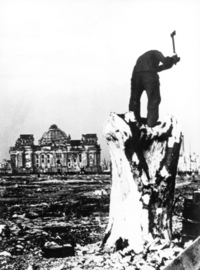 Deutschland im Jahre Null, Filmstill: Ein Mann hackt im zerbombten Berliner Tiergarten einen Baumstumpf. Im Hintergrund ist der zerstörte Reichstag zu sehen. (© picture alliance / Everett Collection)