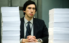 The Report, Szenenbild: Ein Mann im Amzug sitzt an einem Tisch. Neben ihm liegen hohe Papierstapel. (© DCM) 