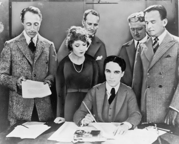 D.W. Griffith, Mary Pickford, Charlie Chaplin (sitzend) und Douglas Fairbanks bei der Unterzeichnung des Gründungsvertrags von United Artists (© Miscellaneous Items in High Demand, PPOC, Library of Congress, Public domain, via Wikimedia Commons)