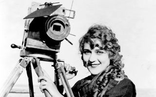 Die Schauspielerin und Filmproduzentin Mary Pickford am Strand mit Kamera um 1916 (© picture alliance/United Archives)