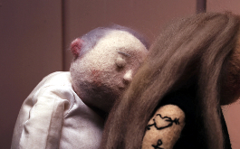 Enough, Szenenbild: Nahaufnahme: Eine männliche Puppe lehnt sich mit geschlossen Augen an den Rücken einer weiblichen Puppe. (© Anna Mantzaris)