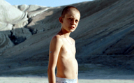 Fauve, Szenenbild: Ein Junge im Teenageralter steht mit nackten Oberkörper in einer Kiesgrube. Er schaut die Betrachtenden direkt an. (© Olivier Gossot)