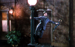 Du sollst mein Glücksstern sein, Szenenbild: Ein Mann tanzt nachts im Regen und hält sich an einer Straßenlaterne fest. (© picture-alliance / Mary Evans Picture Library)