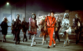Michael Jackson: Thriller, Still aus dem Musikvideo: Der Sänger in rotem Anzug und verfremdeten Gesicht tanzt nachts mit einer Gruppe Zombies. (© Allstar Picture Library Ltd./Alamy Stock Foto)
