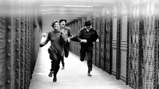 Jules und Jim, Szenenbild: Zwei Männer und eine als Mann verkleidete Frauen rennen lachend über eine Brücke. (© ddp images)