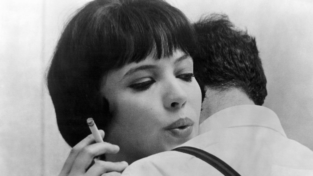 Die Geschichte der Nana S., Szenenbild: Nahaufnahme: Eine junge Frau mit dunklen Haaren umarmt einen Mann und raucht dabei eine Zigarette. (© ddp/Everett Collection)