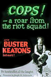 Englisches Filmplakat zum Stummfilm Buster und die Polizei (USA 1922): Das Plakat ist in Grau und Schwarz gehalten. in der unteren rechten Bildecke sitzt der Schauspieler Buster Keaton auf einem Hydranten. In der oberen Bildhälfte steht in grellem Grün "Cops – a roar from the riot squad!", in Rot steht darunter: "It's Buster Keaton's latest!" (© Autor/-in unbekanntUnknown author, Public domain, via Wikimedia Commons)

