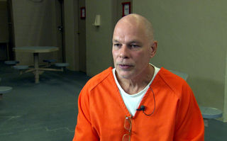 Im Todestrakt, Szenenbild: Ein Mann in orangefarbener Häftlingskleidung (© Werner Herzog Film)
