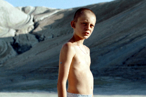 Fauve, Ein Junge im Teenageralter steht mit nackten Oberkörper in einer Kiesgrube. Er schaut die Betrachtenden direkt an. (© Olivier Gossot)
