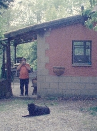 Four Roads, Szenenbild: Ein Mann und ein Hund vor einem kleinen Haus (© MUBI)