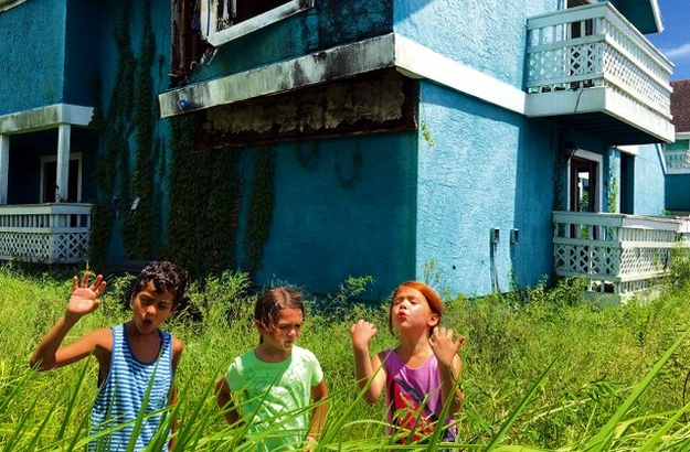 The Florida Project (Szenenbild: Scooty, Monnee und Jancey stehen im hohen Gras, dahinter ein türkisfarbenes Haus. © PROKINO Filmverleih GmbH)