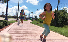 The Florida Project (Szenenbild: Ein Gehweg. Moonee läuft im Vordergrund rechts aus dem Bild. Im Hintergrund ihre Mutter. © PROKINO Filmverleih GmbH)