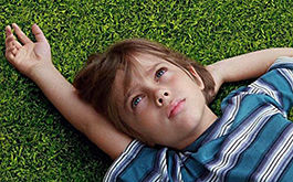 Boyhood (Szenenbild: Naheinstellung eines Jungen. Er liegt im Gras und blickt nach oben. Foto © Universal Pictures)