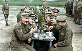 They Shall Not Grow Old, Szenenbild: Soldaten des Ersten Weltkriegs sitzen an einem Tisch und lachen in die Kamera. Das Bild ist coloriert. (© Imperial War Museum/ Warner Bros. Pictures)