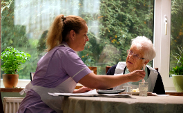 Soory We Missed You, Szenenbild: Eine Frau sitzt an einem Tisch und füttert eine alte Dame. (© JOSS BARRATT)