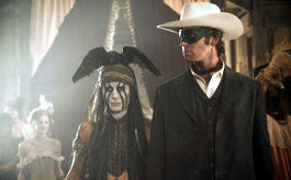 Lone Ranger, Szenenbild: Ein indigener Mann mit angemalten Gesicht und einer Krähe auf dem Kopf steht neben einem weißen Mann im Anzug. Dieser trägt eine schwarze Augenmaske. (© Walt Disney Motion Pictures))