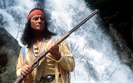 Winnetou, Szenenbild: Der Apachen-Häüptling Winnetou (Pierre Brice) steht mit seinem Gewehr vor einem Wasserfall (© picture-alliance / dpa)