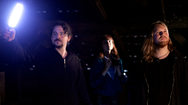 Endlich Tacheles, Szenenbild: Zwei junge Männer und im Hintergrund eine junge Frau stehen in der Dunkelheit, spärlich beleuchtet. Einer hält eine leuchtende Stablampe. (© Schramm Matthes Film)