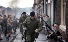 71, Szenenbild: Ein britischer Soldat läuft geduckt auf die Kamera zu, neben ihn läuft ein Junge mit Gewehr. In der Straße herrscht Chaos (© picture alliance / dpa / Berlinale)