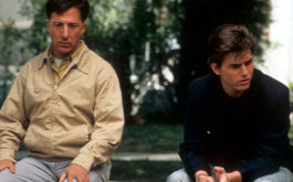 Rain Man, Szenenbild: Zwei Männer sitzen nebeneinander auf der Bank: Der eine blickt abwesend, der andere besorgt. (© Picture Alliance)