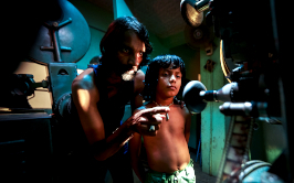 Das Licht, aus dem die Träume sind, Szenenbild: In einem dunklen Kino-Vorführraum zeigt ein Mann einem Jungen den Filmprojektor. (© Neue Visionen)