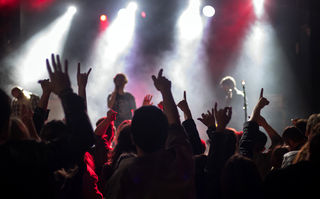 Frieden, Liebe und Death Metal, Szenenbild: Blick auf einer Konzertbühne vom Publikumsraum aus; im Gegenlicht sieht man erhobene Arme der Zuschauer/-innen (© Studiocanal)