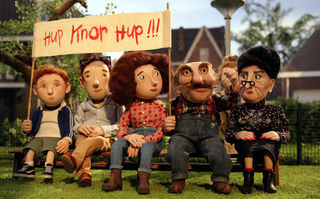 Oink, Szenenbild aus dem Puppentrickfilm: Auf einer Bank sitzen fünf Figuren unterschiedlichen Alters. Sie halten ein Plakat in die Höhe. (© Kinostar Filmverleih GmbH)