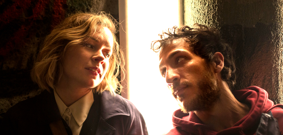 Orphea in Love, Szenenbild: Eine junge Frau und ein junger Mann sitzen nebeneinander in einem dunklen Raum und schauen sich an. (© missingfilms)
