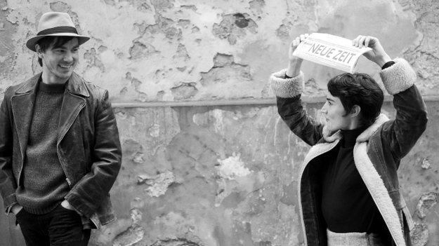 Lieber Thomas, Szenenbild: Ein junger Mann mit Hut lacht eine kurzhaarige Frau an, die eine Zeitung über ihren Kopf hält. (© Zeitsprung Pictures / Wild Bunch Germany (Foto: Peter Hartwig)