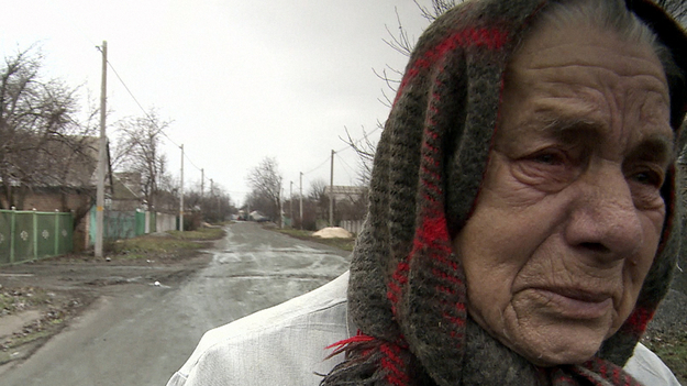 Meine Mutter, ein Krieg und ich, Szenenbild: Nahaufnahme einer alten Dame mit Kopftuch auf einer Straße. Sie wirkt verstört. (© Johann Feindt Filmproduktion)