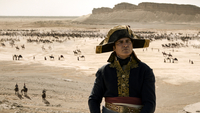 Napoleon, Szenenbild: Der französische Kaiser Napolepon steht vor einer weiten Wüstenlandschaft, in der verstreut Soldaten zu sehen sind. (© 2023 Sony Pictures Entertainment Deutschland)