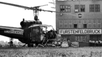 Tod und Spiele - München '72, Szenenbild: Ein ausgebrandter Helicopter mit der Aufschrift "Bundesgrenzschutz" steht vor einem Flughafengebäude mit dem Schriftzug "Fürstenfeldbrück" (© ARD/rbb/IMAGO-Heinz Gebhardt)