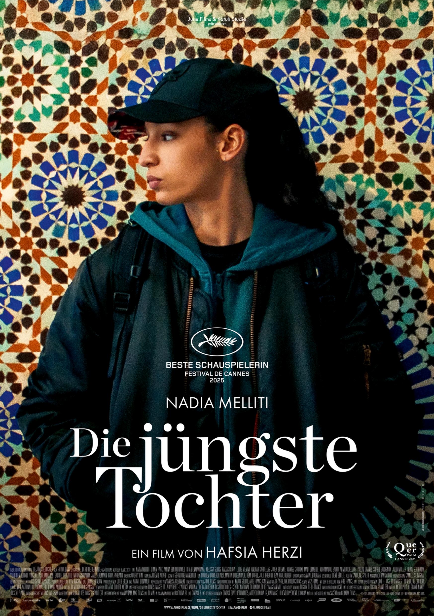 Filmplakat zum Drama DIE JÜNGSTE TOCHTER: Eine junge, schwarz gekleidete Frau steht vor einer Wand mit bunten Fliesen. Sie trägt eine Basecap und schaut ernst zur Seite.