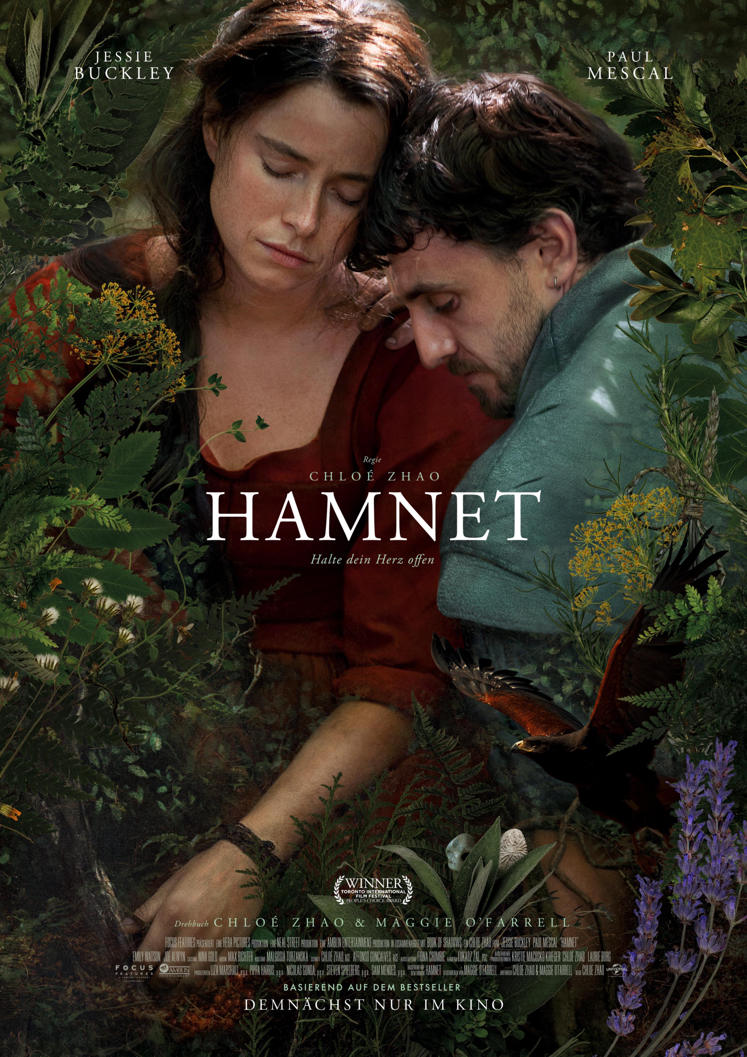 Filmplakat zum Drama HAMNET: Eine Frau im roten Kleid und ein blau gekleideter Mann sitzen eng aneinander geschmiegt zwischen Büschen und Farnen. Sie haben die Augen geschlossen. Der Titel steht in der Bildmitte in weißen Buchstaben. 