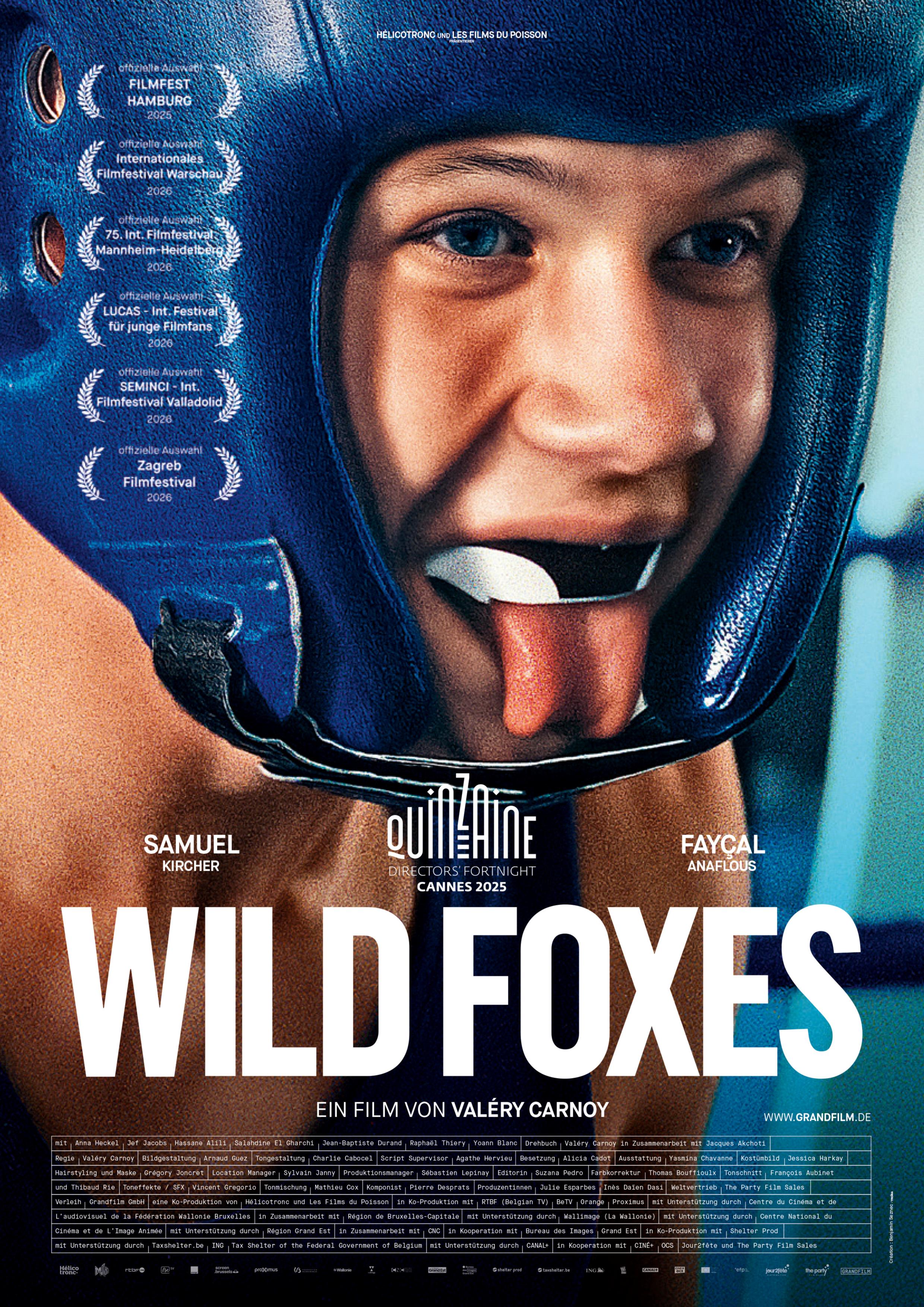 Plakat zum Drama WILD FOXES: Bildfüllend ist das Gesicht eines jungen Mannes zu sehen, der einen Boxhelm und eine Beißschiene trägt. Er steckt die Zunge heraus. Darunter steht in großen weißen Buchstaben der Filmtitel.