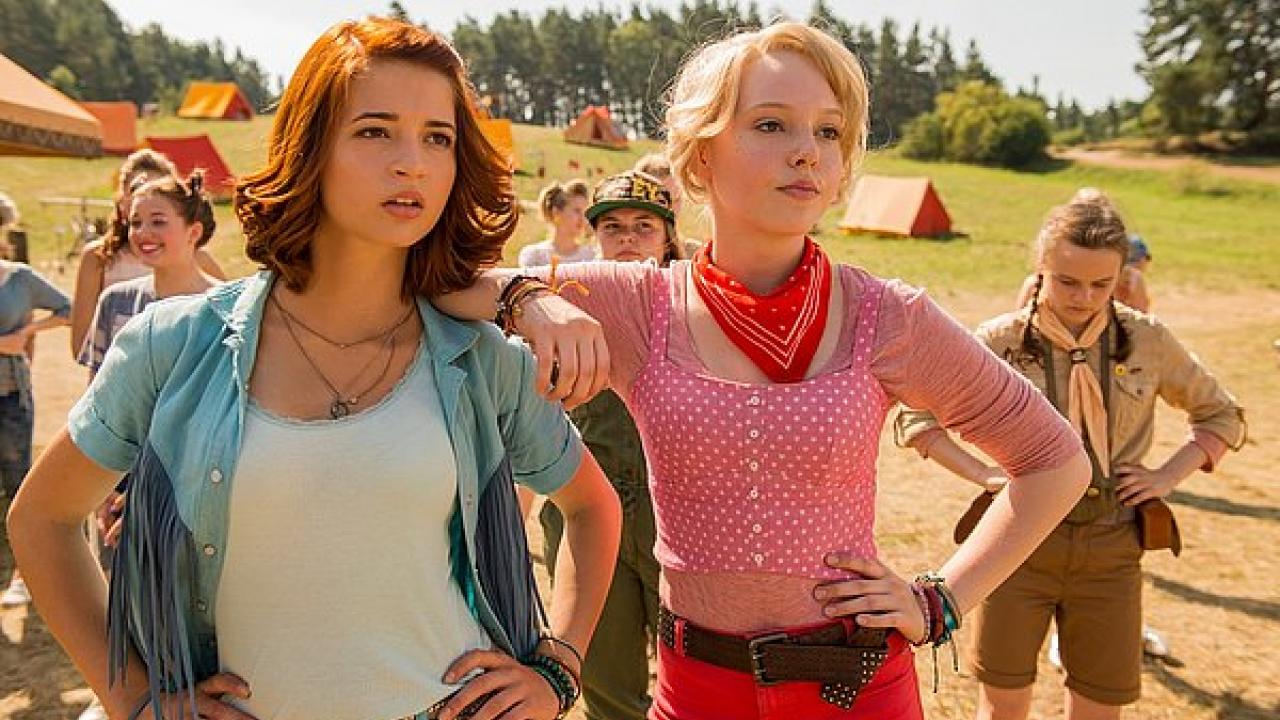 Ein rothaariges Mädchen und ein blondes Mädchen stehen neben einander und gucken frech vor sich hin