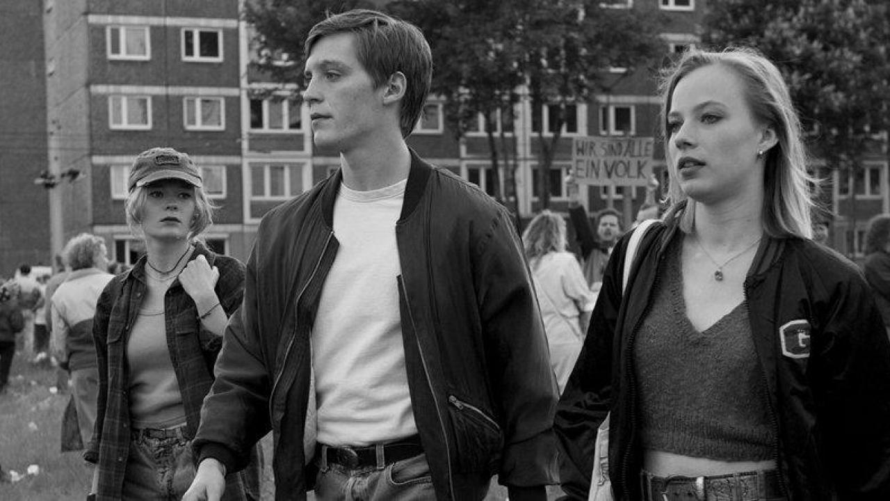 In Schwarz-Weiss: ein junger Mann und eine junge Frau laufen nebeneinander inmitten einer Demo