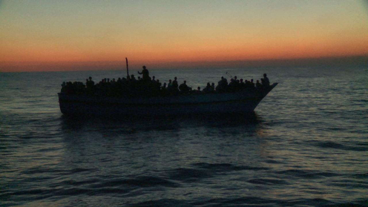 Eldorado, Szenenbild: Ein Flüchtlingsboot auf dem Meer im Sonnenunterngang als Silhouette
