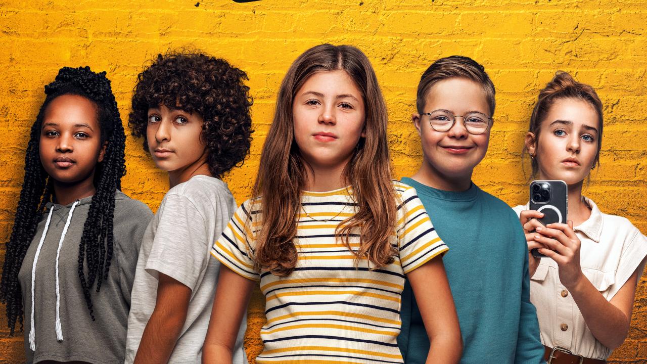 Ausschnitt aus dem Filmplakat zu LARS IST LOL: Plakat zum Film LARS IST LOL: Drei Mädchen und zwei Jungen im Teenageralter stehen vor einer gelb angestrichenenn Mauer. Der eine Junge hat Down-Syndrom, ein Mädchen hält ein Smartphone in den Händen.