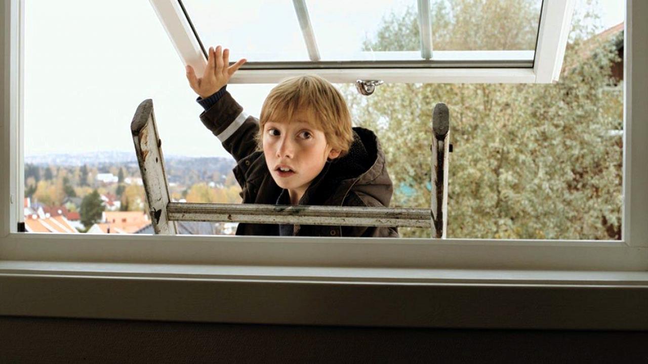 Still aus dem Kinderfilm THE LIVERPOOL GOALIE: Eine Junge steht auf einer Leiter und öffnet ein Fenster. Die Aufnahme ist aus dem Zimmer heraus gemacht worden.