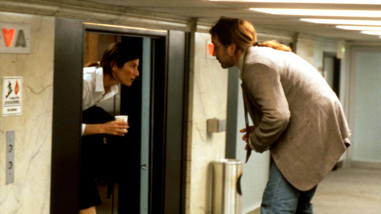 Filmstill aus BEING JOHN MALKOVICH: Eine Frau tritt aus einem Fahrstuhl, ein Mann möchte offenbar hinein. Die Decken sind sehr tief, so dass beide Personen sich nur in gebückter Haltung fortbewegen können.